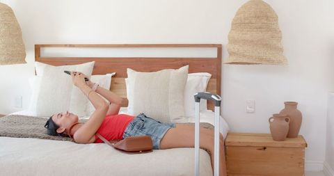 Woman relaxing on bed with smartphone in cozy modern room