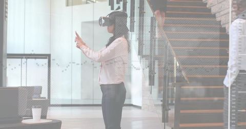 Businesswoman wearing vr headset interacting with virtual interface in modern office lobby
