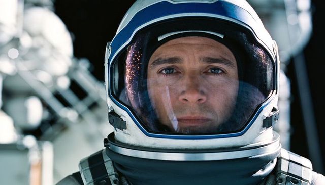 Focused astronaut portrait wearing white-blue helmet reflecting launchpad lights