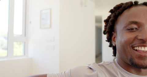 African american man smiling in bright modern interior by multi-pane window, copy space