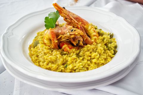 Gourmet seafood risotto with prawn garnish on white plate