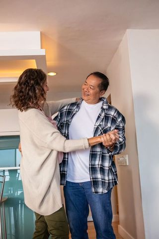 Diverse couple dancing joyfully at home under warm recessed lights