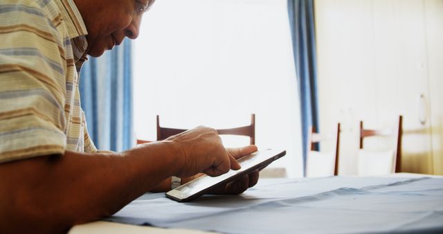 Middle-Aged Man Using Tablet Device in Sunlit Room - Download Free Stock Images Pikwizard.com