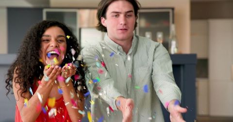 Joyful Interracial Couple Celebrating with Colorful Confetti at Home Party