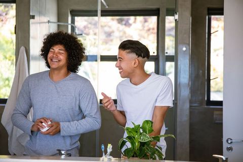 Diverse Friends Laughing by Bathroom Sink Enjoying Morning Routine
