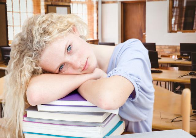 Digital composition of a girl resting her head on stack of books in classroom