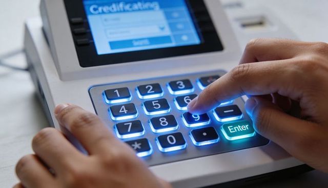 Retail payment terminal keypad being pressed by hand with backlit blue numeric buttons
