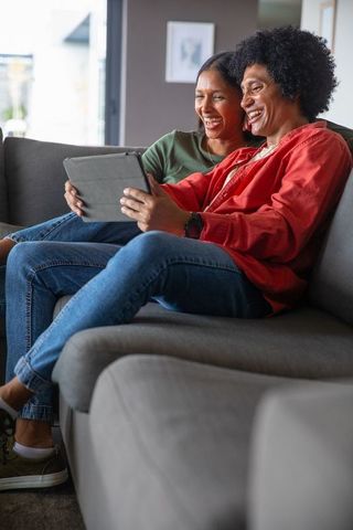 Happy Diverse Couple Relaxing on Sofa with Tablet in Living Room
