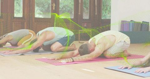 Group yoga class practicing child's pose on colorful mats in sunny wellness studio