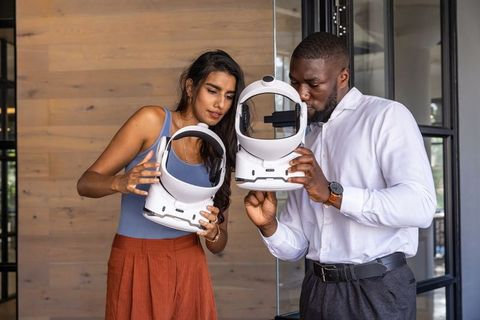 Diverse coworkers inspecting vr headset in modern office