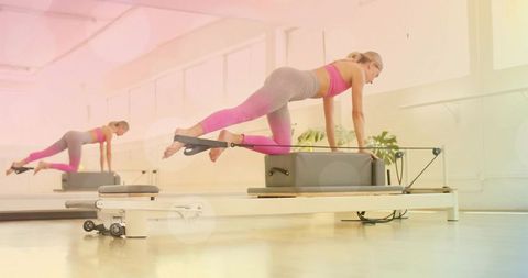 Balancing core strength on pilates reformer box in bright mirrored studio
