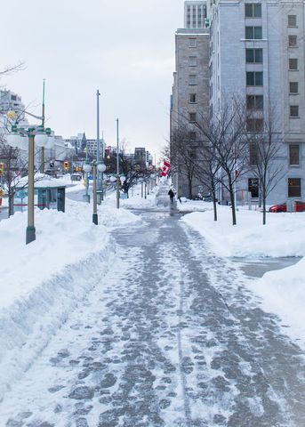 Downtown Winter Sidewalk Clearing Walking Path Flanked by Snowbanks and City Buildings