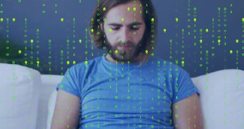 Man sitting on couch viewing floating green binary code overlay, contemplating tech at home
