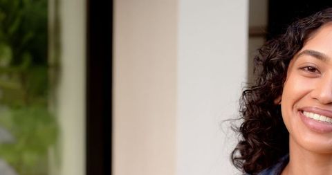 Smiling Woman with Curly Hair Near Modern Architecture