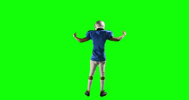 Football player wearing blue uniform and white pants, flexing his muscles on green screen background. Man is dressed in helmet and sports gear. Perfect for sports promotion, fitness advertisements, or digital effects where background removal is needed.
