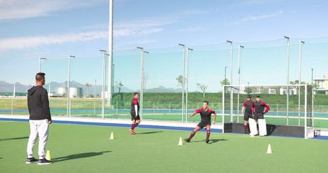 Field Hockey Coach Conducts Drill Session with Teen Players on Turf