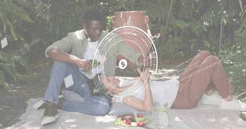 Couple relaxing on picnic blanket in backyard with futuristic hud overlay and refreshments