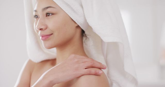 Image of portrait of smiling biracial woman with towel on hair in bathroom. Health and beauty, leisure time, domestic life and lifestyle concept.