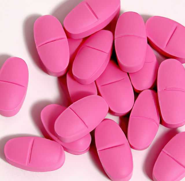 Close up of multiple pink pills laying on white background. Medicine, healthcare and treatment concept.