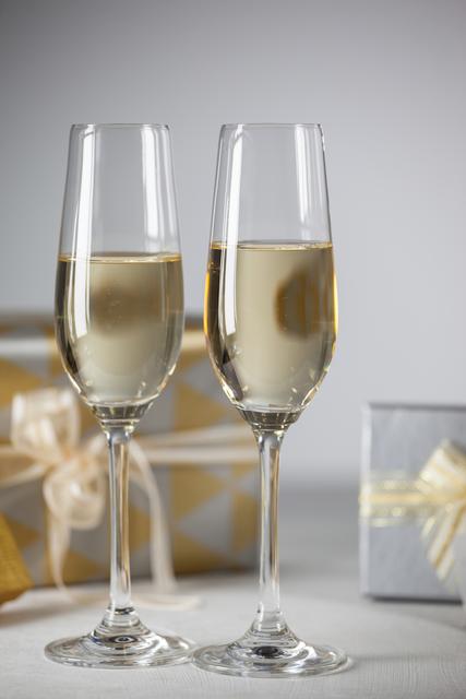 Two champagne flutes and Christmas gifts against white background