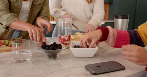 Diverse Group Preparing Fresh Fruit Smoothies in Modern Kitchen