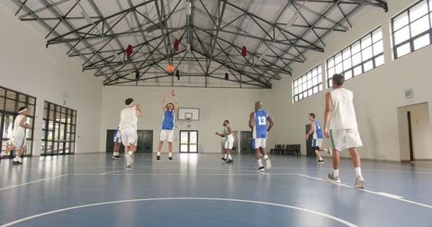 Athletes Playing Energetic Basketball Game in Modern Gymnasium