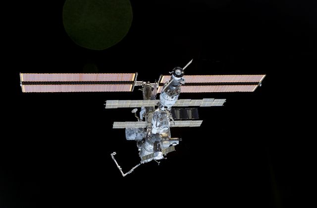This image captures the International Space Station with its newly installed 27,000-pound S0 truss during the STS-110 mission in 2002. Showing the intricate framework and advancements for future spacewalks, this photo can be used for educational materials, documentaries, aerospace engineering presentations, and discussion about space exploration advancements. Highlighting NASA's effort in building the first space railroad and the robust construction of the ISS, it serves ideal for enthusiasts and professionals in the astronomy and aerospace communities.