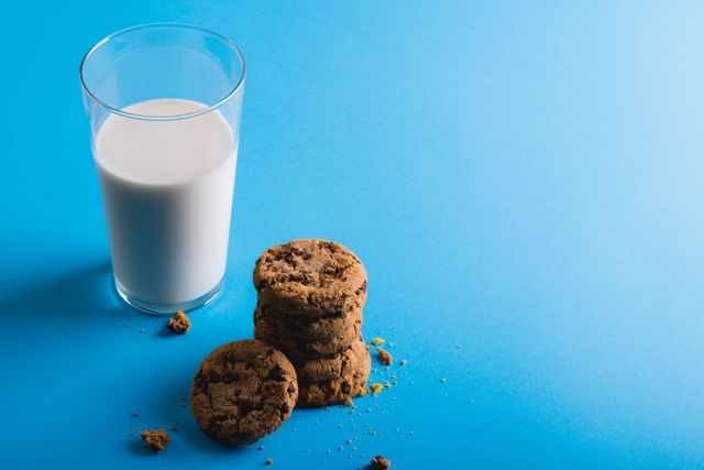 High angle view of milk glass with cookies over blue background with copy space. unaltered, food, drink, studio shot and healthy eating.