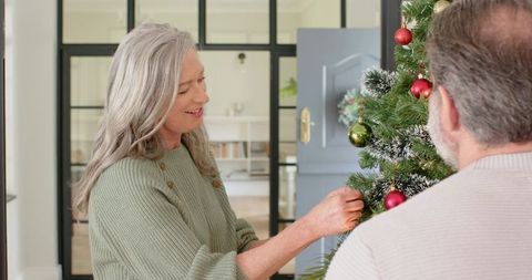 Senior Couple Enjoying Holiday Tradition of Decorating Christmas Tree