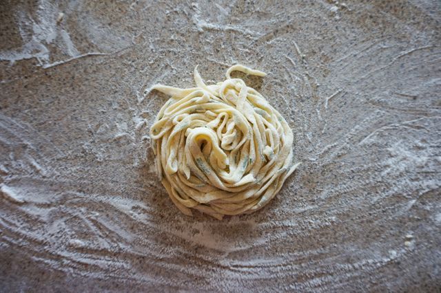 Close-up of fresh homemade pasta dough arranged in a nest on a floured countertop. Suitable for illustrating recipes, cooking blogs, Italian cuisine, culinary websites, and food-related magazines.