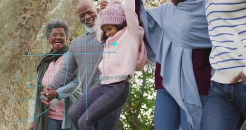 Multigenerational Family Lifting Girl Holding Hands in Autumn Park Sharing Togetherness