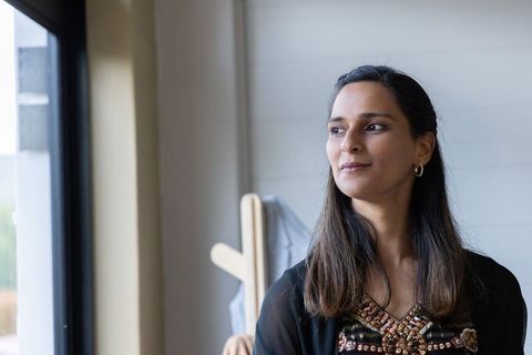 Indian woman standing by window looking thoughtful in modern home interior portrait