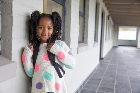 Smiling young girl with backpack in school corridor