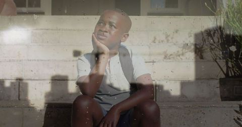 Reflective boy sitting on stairs amid cityscape overlay