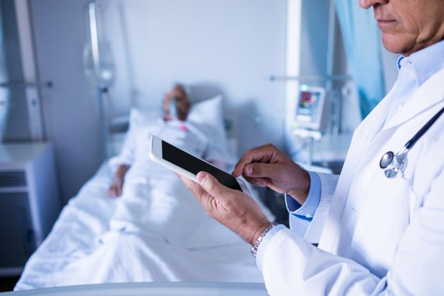 Mid-section of male doctor using digital tablet in the hospital