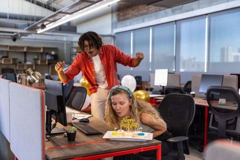 Coworkers celebrating birthday in modern open office
