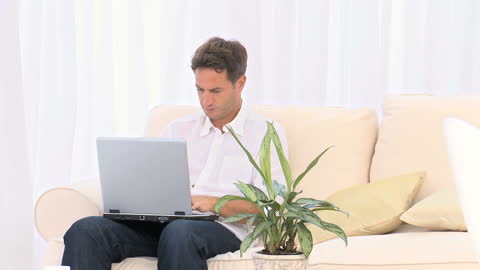 Man Focused on Laptop While Sitting on Cozy Couch