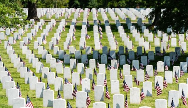 American flags lining white military headstones in memorial cemetery memorial day rows