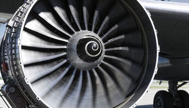 Close-up turbofan engine fan spinning on airport apron with spiral spinner and gear macro