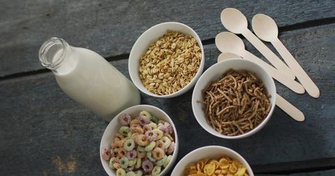 Displaying Rustic Breakfast Cereal Variety with Milk Bottle and Wooden Spoons Flatlay