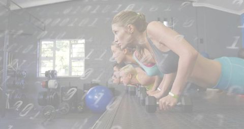 Women performing push-ups on hex dumbbells in group strength training class