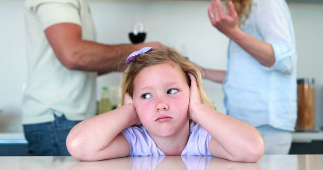 This image depicts a young girl in a kitchen, visibly upset and covering her ears while ignoring her parents arguing in the background. Suitable for illustrating concepts of family conflict, emotional stress in children, and domestic strife. May be used in articles relating to child psychology, family counseling, and the impact of parental conflicts on children.