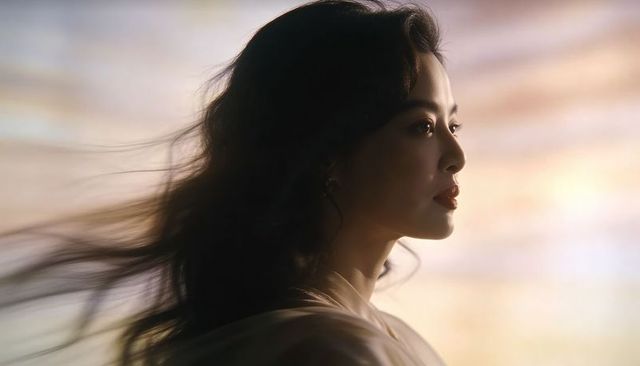 Asian woman gazing in profile with windblown hair and warm rim light cinematic portrait