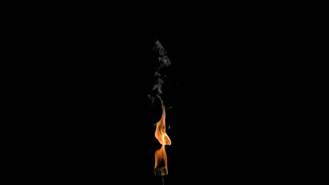 Burning flame with rising, graceful smoke against a dark backdrop. Suitable for illustrating concepts of fire safety, meditation themes, or creating atmospheric promotional material.