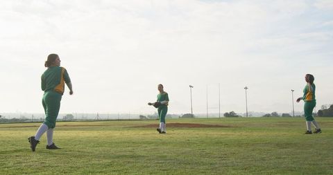 Female softball teammates practicing on field at sunrise
