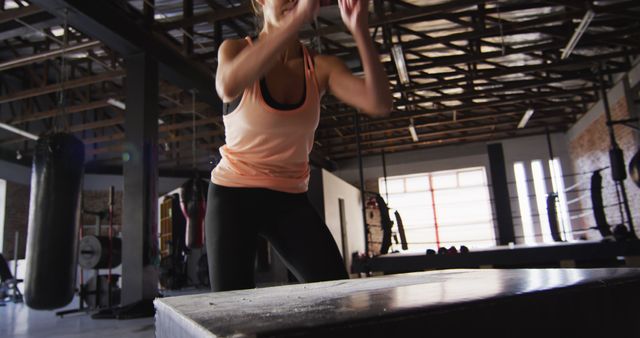 Fit woman performing box jumps in a modern gym. Can be used for illustrating workout routines, fitness motivation, health and wellness blogs, and sports training programs.