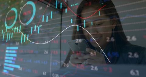 Businesswoman analyzing financial data on smartphone and wall charts