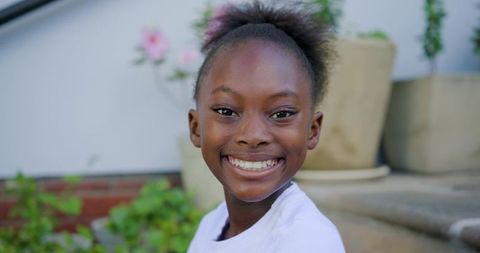 Smiling young girl posing on front steps wearing light crewneck shirt