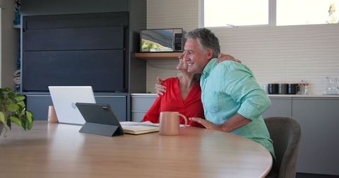 Joyful senior couple video calling on laptop at home