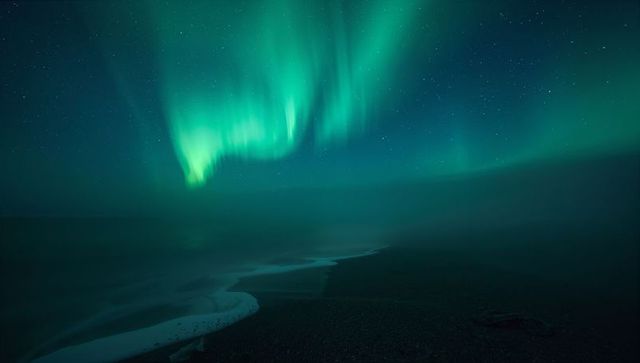 Dancing Northern Lights over Misty Shoreline with Teal Auroral Curtains